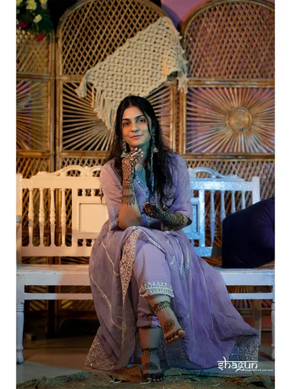 The bride showing off her intricate mehndi design. The rustic, bohemian-style background complements her lavender outfit perfectly.