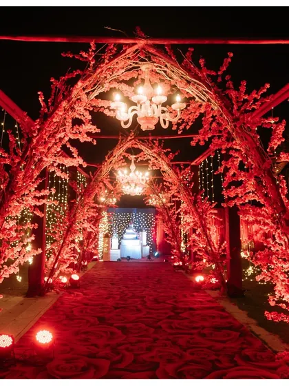 A breathtaking entrance for a night to remember. We designed this stunning red floral tunnel, complete with elegant chandeliers, to create a grand and romantic welcome for a reception at Sula Vineyards.