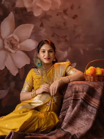 A beautiful studio portrait in a yellow saree, with a floral backdrop and traditional props like a marigold basket, perfect for a seemantha or baby shower theme.