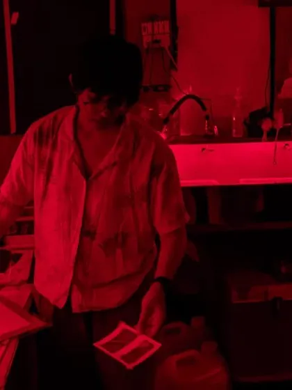 The magical red glow of the darkroom during a printing session for the Our Shared Cultural Heritage project. This is where images come to life through careful, hands-on work.