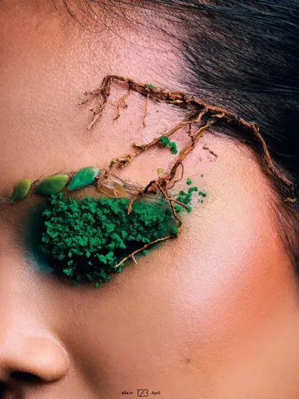 An extreme close-up on the model's eye, showcasing the detailed application of green moss eyeshadow and delicate root-like structures. This image provides a focused look at the intricate makeup artistry central to the editorial.