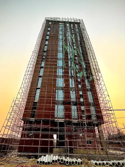 A direct, frontal view of the same office tower under construction. This perspective clearly shows the grid-like pattern of the windows set within the expansive brick facade, a key element of this energy-efficient design.