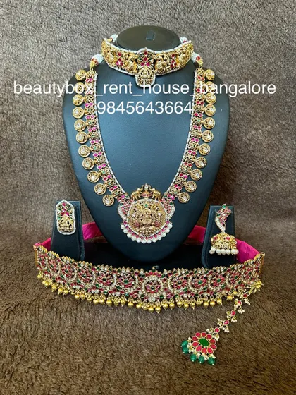 A kasu haram set with a unique temple pendant, paired with a matching choker and a kemp stone vaddanam.