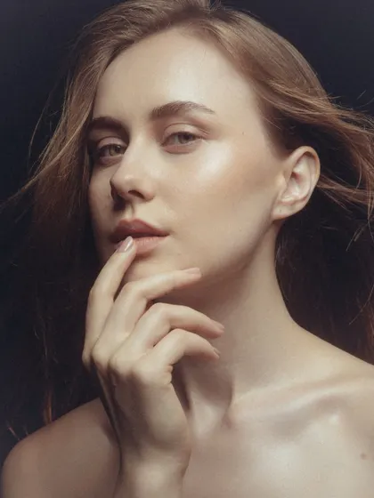 A classic beauty pose. The makeup is clean and timeless, with a focus on flawless skin and a natural finish.