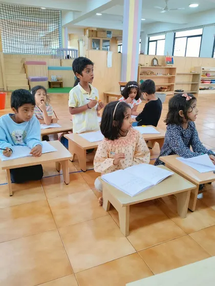 Children sit at tables, working on their writing together. While much of our work is individual, we also provide opportunities for collaborative learning and peer interaction.