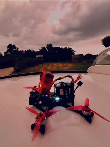 A custom-built FPV drone with an action camera mount, resting on a car hood against a dramatic sunset. This is the kind of personalized, high-performance machine you can learn to build.