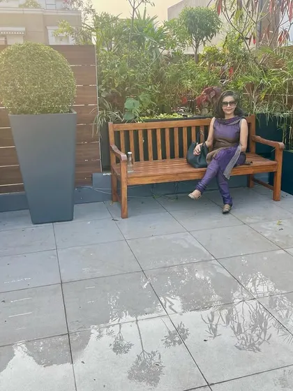 Relaxing on a wooden bench in the newly completed GK rooftop garden. The space is defined by a wooden screen and a mix of tall and round topiary planters.