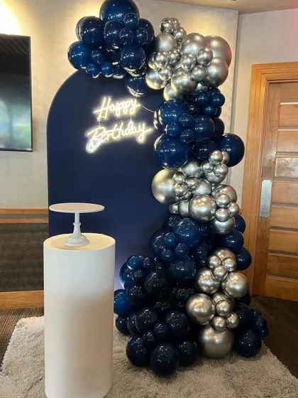 This chic and simple backdrop is perfect for adult birthdays. The navy arch, premium balloon garland, and cake plinth create an elegant focal point.