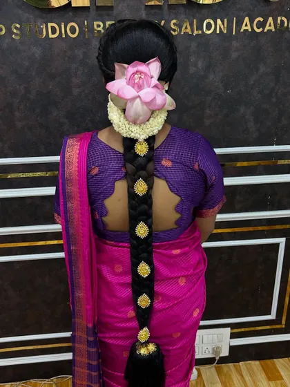 This is my specialty, an intricate 'poola jada' or floral braid. Here, a traditional braid is adorned with jasmine flowers and a fresh lotus, creating a truly divine look for a South Indian bride.