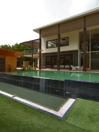 The pool area of the Sachdeva Farmhouse is a multi-level experience. The gym and spa open directly onto this central zone, with steps leading up to a terrace garden, creating a fluid connection between leisure, wellness, and nature.