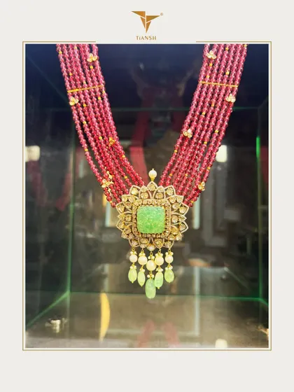 A stunning fusion of ruby strands and a carved jade centerpiece, framed in gold and Polki. This necklace speaks the language of regal tradition with its bold hues and timeless artistry.