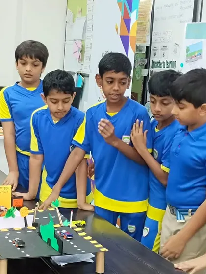 Students gather around a model of a city street, learning about civil engineering and urban planning concepts in a tangible, interactive way.