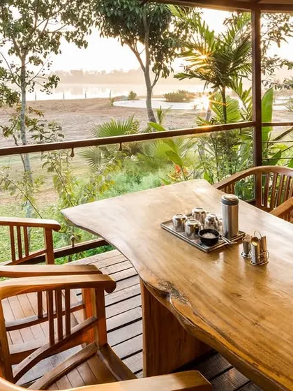 A stunning solid wood dining table on a deck overlooking the Kabini backwaters, offering an unparalleled dining experience.