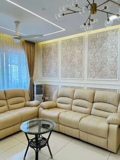 This living room features comfortable leatherette recliner sofas set against a wall with textured wallpaper and classic white molding, creating a look of timeless elegance.