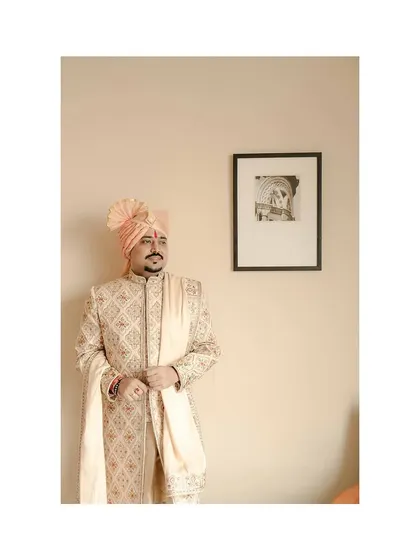 A solo portrait of the groom, looking thoughtful and handsome in his wedding sherwani.