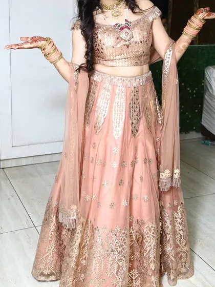 Another look at the peach off-shoulder lehenga, highlighting the delicate tassels on the blouse and the gold embroidery on the skirt.