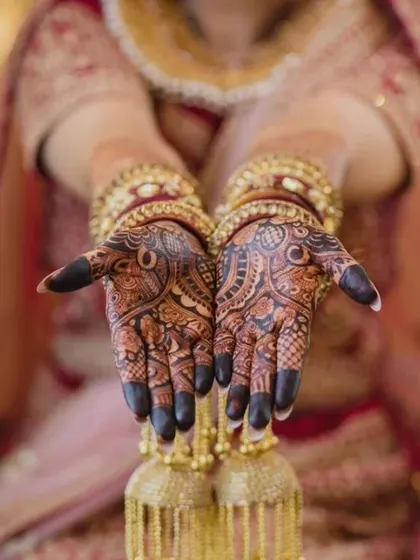 A close-up shot of a bride's hands, adorned with traditional jewelry that complements the dark henna stain. This is the picture-perfect bridal look I aim for.