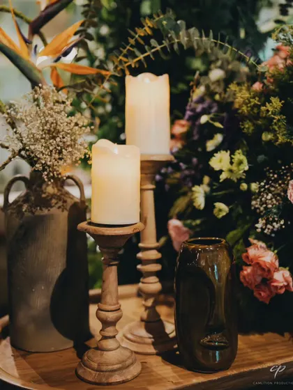 A close-up of the decor details, featuring textured vases, pillar candles, and unique face-sculpture props that add an eclectic and artistic touch to the table setting.