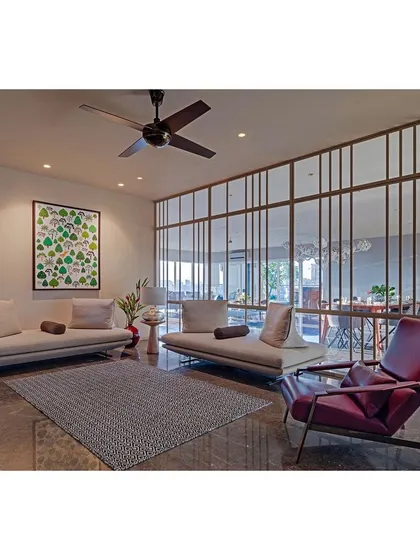 Another view of the Sky Residence, showing a more relaxed seating area. The space is defined by a metal and glass screen that separates it from the dining area without blocking light, maintaining an open and airy feel.