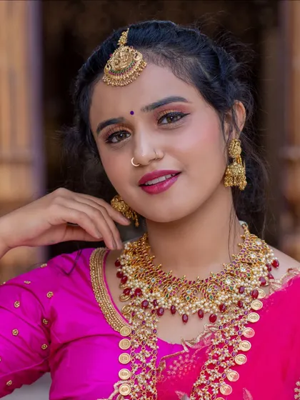 A close-up of a model wearing a ruby-studded guttapusalu necklace and matching jhumkas, available for rent.