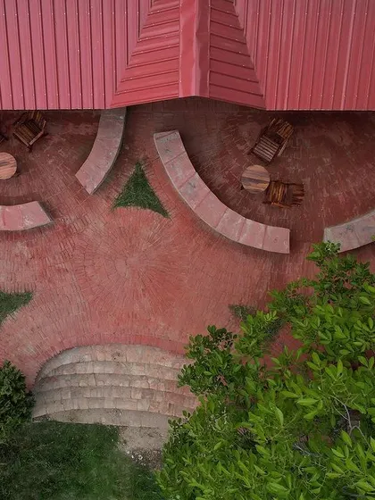 An aerial view of the outdoor seating area at Sargakhet, showing the concentric brick flooring and stone benches that complement the natural landscape and the restored heritage building.