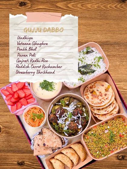 A detailed look inside my Gujju Dabbo. This image shows the complete meal, including Undhiyu, Vataana Ghughra, Ponkh Bhel, Puran Poli, and Strawberry Shrikhand, with a handwritten menu list.