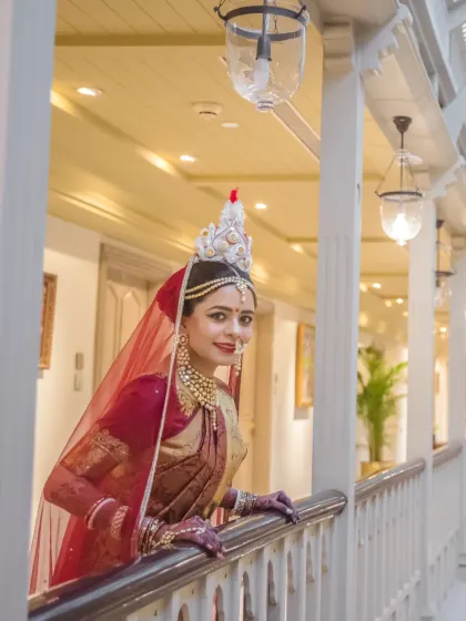 A stunning portrait of a traditional Bengali bride. Her classic attire and the elegant architectural setting combine for a picture of timeless grace.