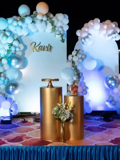 A sweet and simple Baby Mickey Mouse theme. This setup uses a soft blue and white color palette with balloon clouds, gold pedestals for the cake, and a cute cutout of baby Mickey.