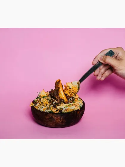 This action shot shows a spoonful of biryani being lifted from the bowl, adding a dynamic and engaging element. It helps customers visualize the texture and portion of the dish.