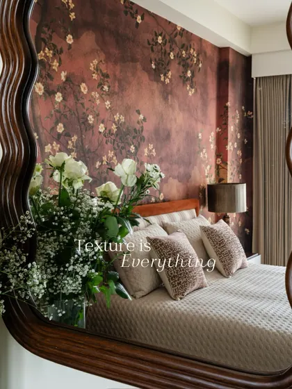 This bedroom wall is enveloped in a moody, textured wallpaper with scattered blossoms. The design, reflected in the mirror, creates a romantic and immersive atmosphere.