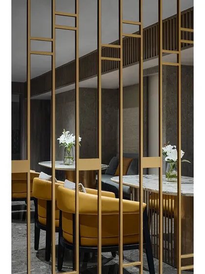 The mezzanine level at the Blue Sea Banquet, now a functional space for discussions or small gatherings. The design continues the theme of mirrored panels and metal jalis, with comfortable yellow armchairs adding a pop of color.
