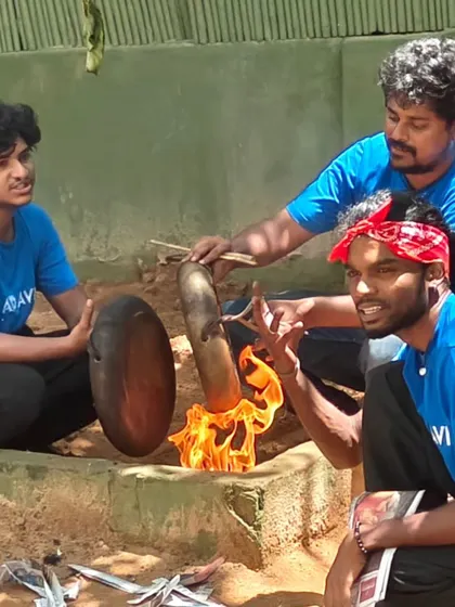 Instructors from Adavi Arts Collective perform a traditional ritual, warming the parai drum over a fire before the performance begins.
