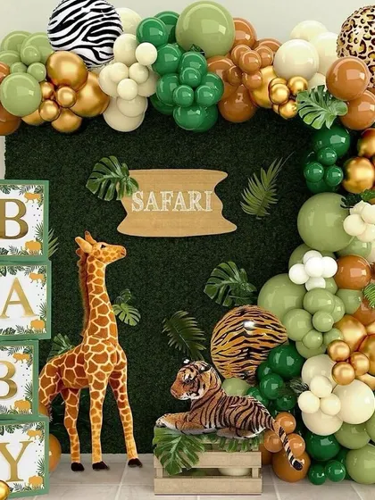 Let's go on an adventure with a Safari themed baby shower. This fun setup includes a boxwood hedge backdrop, a balloon garland in jungle tones of green, gold, and brown with animal prints, and cute props like a giraffe and tiger to bring the wild theme to life.