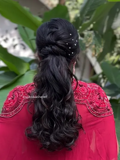 A stylish and modern ponytail with a twisted crown and voluminous curls. This is a very popular choice for cocktail parties and engagements.