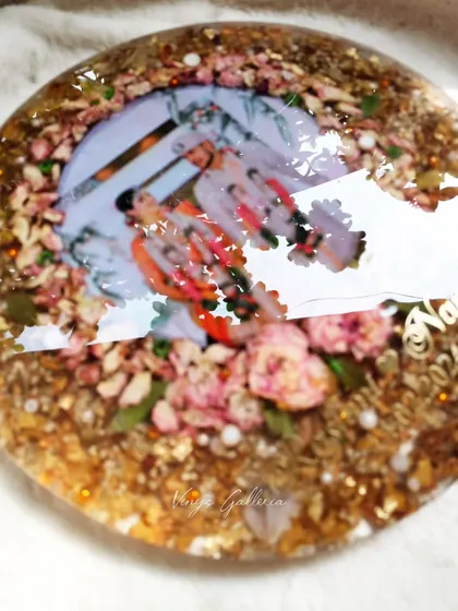 The glossy finish on the round floral frame, reflecting light and showing the depth of the preserved flowers.
