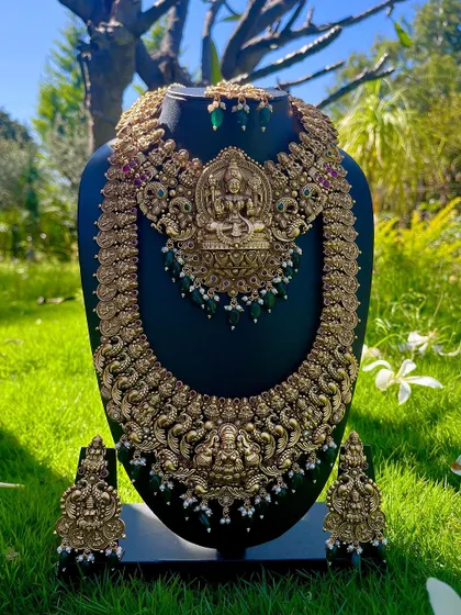 This grand temple jewellery set features a statement choker and a matching long haaram with a large Lakshmi pendant. It's a premium rental piece for a traditional wedding.