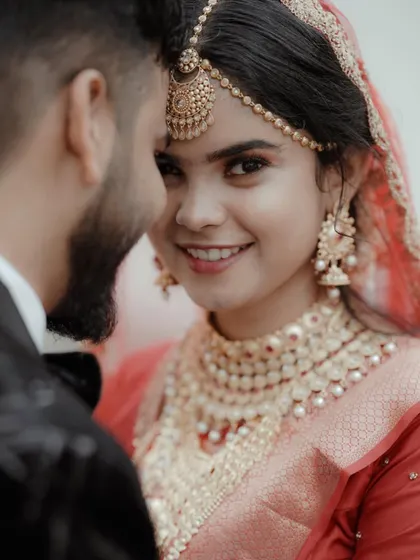 An intimate over-the-shoulder shot, focusing on the bride's beautiful smile as she looks at her groom.