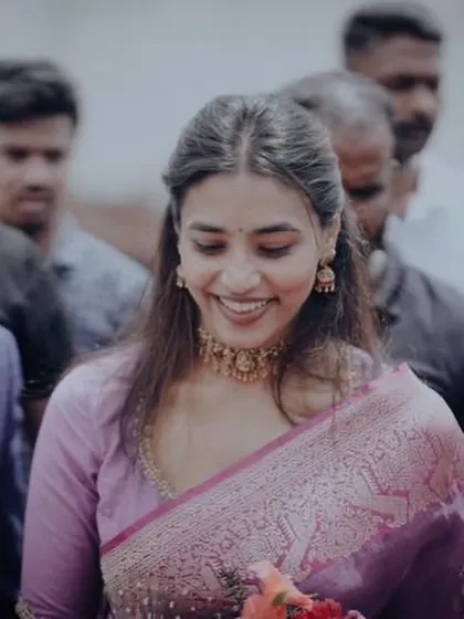 A candid shot of our client, her smile lighting up the frame, dressed in a lovely purple saree.