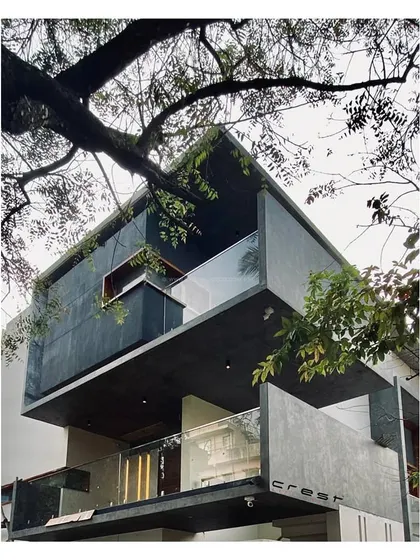 'Residence 97' nearing completion, nestled among trees. The dark-clad upper volume and cantilevered balconies are already defining its character.