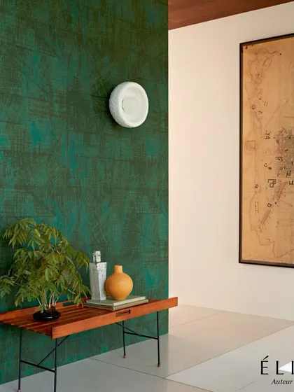 The 'Kandy' wallpaper from Élitis, with its wood-grain effect in a deep emerald green, adds organic texture and rich color to this modern space. It serves as a perfect example of how nature-inspired designs can feel contemporary and luxurious.