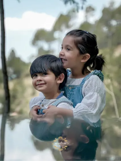 A sweet moment between siblings, with the older sister giving her brother a hug. The reflection adds a creative touch to this outdoor portrait.