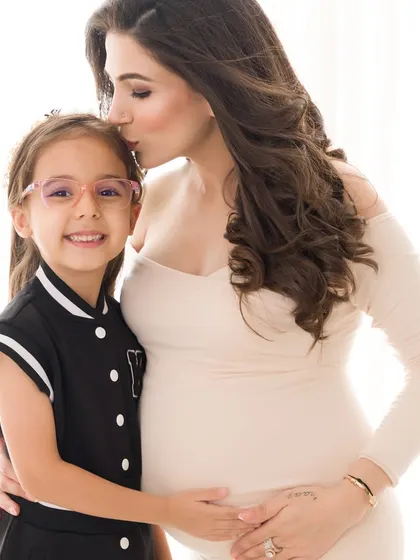 A mother's gentle kiss for her daughter during their maternity session. This image captures the soft, loving bond between them as they await a new family member.
