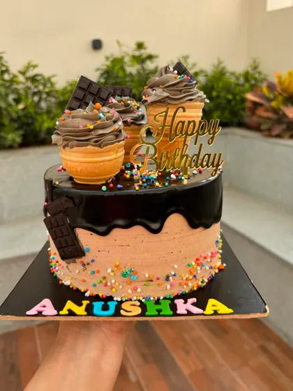 This chocolate overload cake features mini ice cream cone cakes on top, along with chocolate bars and sprinkles. It's a dream for any chocolate lover.