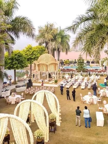 An elegant lakeside wedding setup at Shikarbadi Hotel, Udaipur. The golden-domed mandap stands beautifully against the serene water, creating a picturesque setting for the pheras.