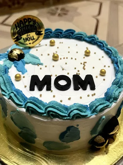 A lovely cake for "MOM" with a blue and white watercolor buttercream finish. It's personalized with bold lettering and decorated with golden pearls for a touch of sparkle.
