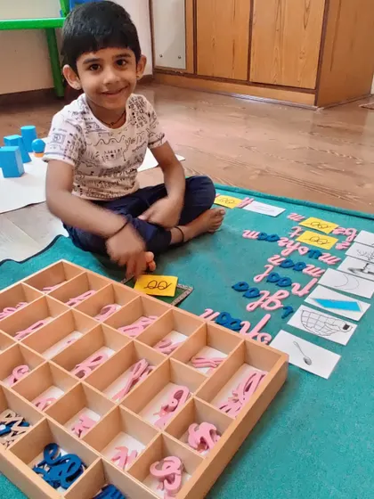 A child works with the movable alphabet to build words based on phonetic sounds. This hands-on approach to spelling and reading makes the process of learning language intuitive and enjoyable.