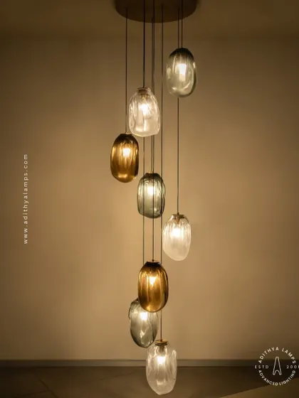 This cascading installation features pendants made of organic, free-form glass in smoked and amber tones. The textured, irregular shapes create a beautiful, water-like effect, perfect for adding a sense of calm and artistry to a room.