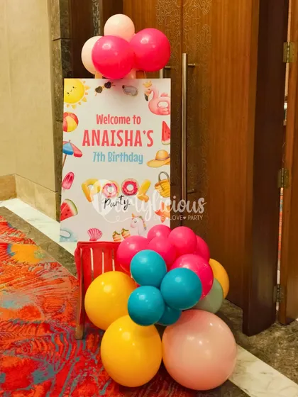 A cheerful welcome sign for Anaisha's 7th birthday pool party, decorated with a small bunch of colorful balloons.