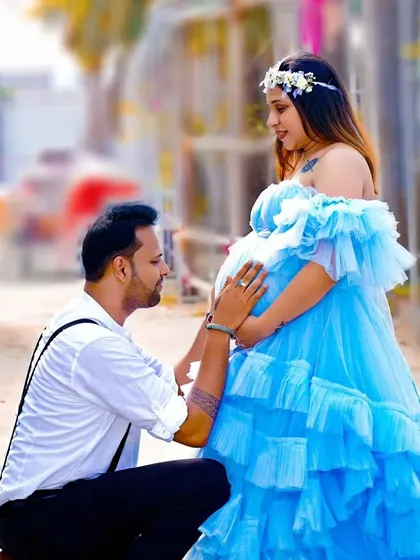 A sweet moment between an expecting couple. The mom-to-be looks radiant in a sky-blue ruffled gown, a popular choice for its romantic and whimsical feel.