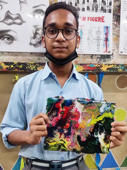 A young student with his first fluid art piece. Our classes are open to all ages, providing a fun and accessible way to explore abstract painting.